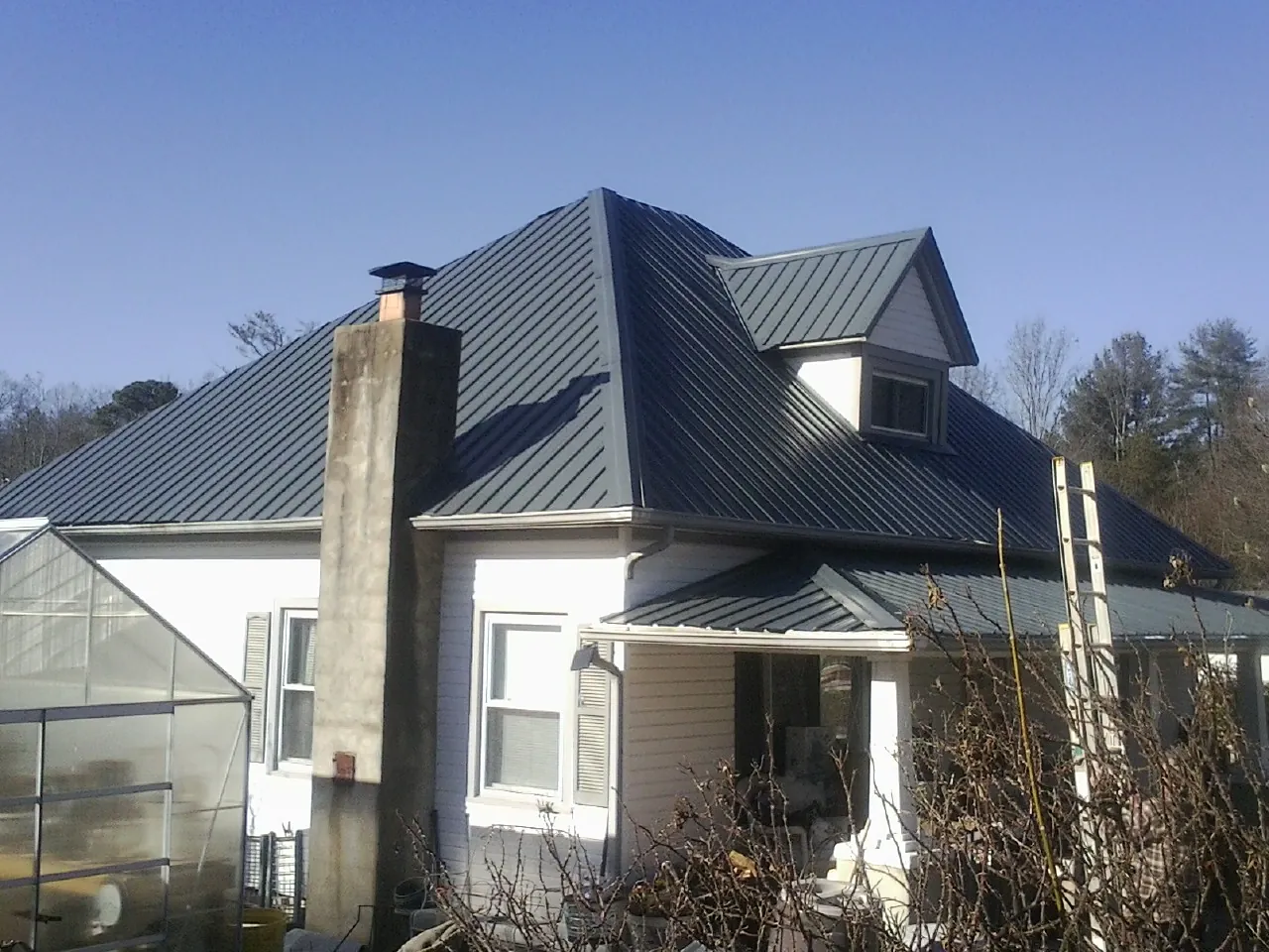 Dark blue standing seam metal roof on a white farmhouse with dormer — Slate & Tile Roof Repair by Roofing Brothers in Klamath Falls