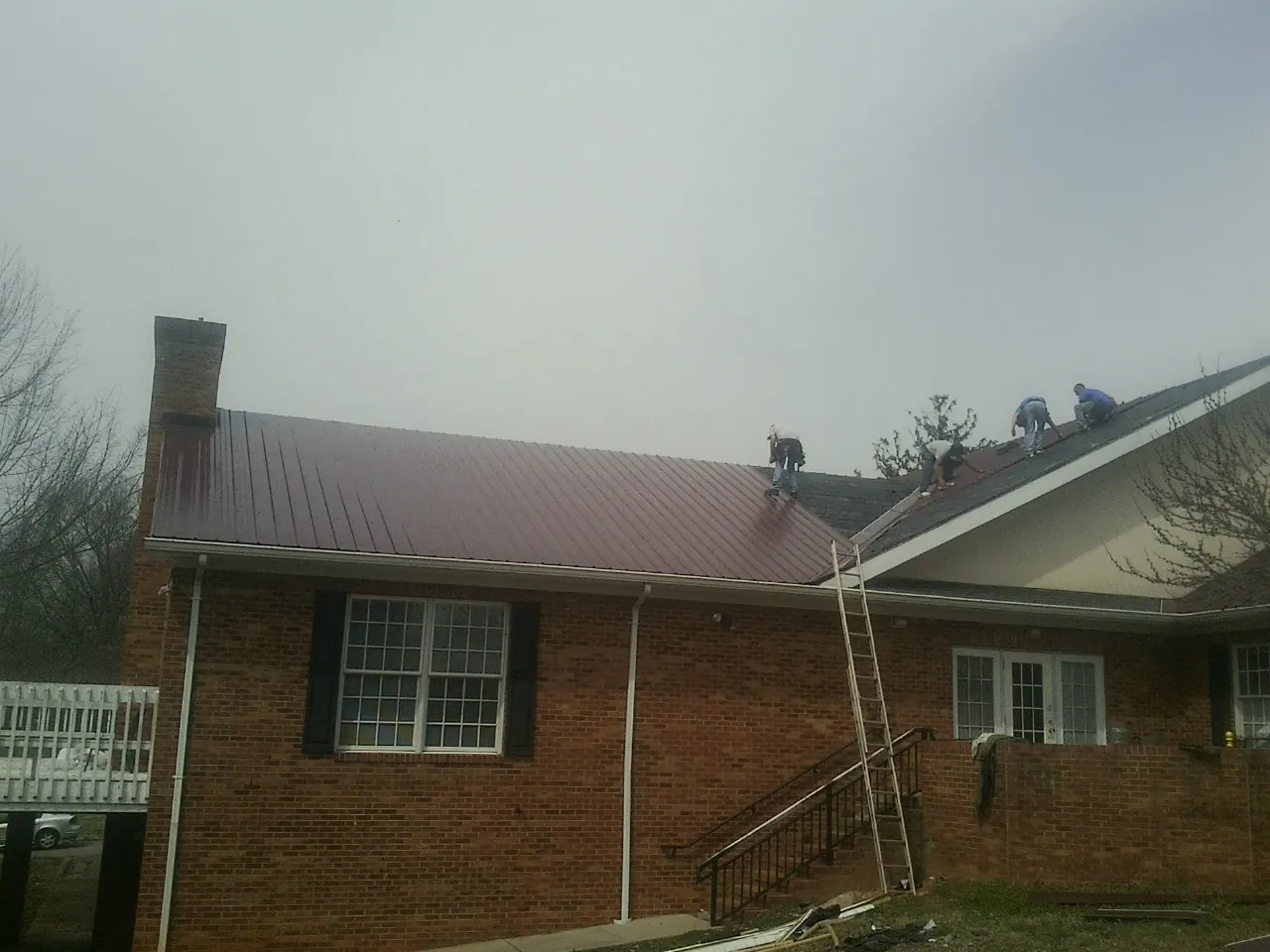 Crew setting red metal roofing panels on a brick home in Klamath Falls