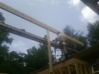 Carpenter setting a ridge beam over a new addition frame — Ice Dam Removal by Roofing Brothers in Klamath Falls