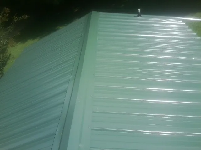 New green metal panels meeting at the ridge of a roof — Flat Roof Repair work by our crew in Klamath Falls