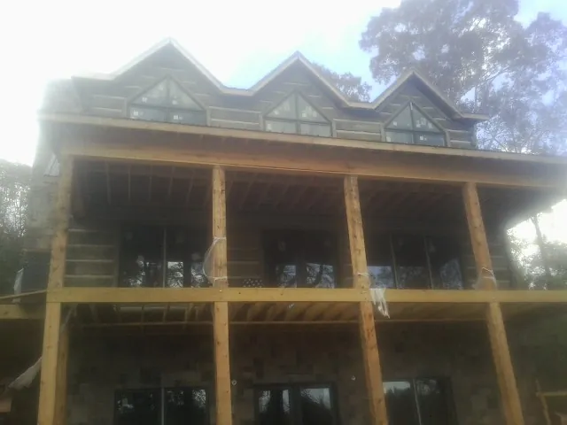 Dormers and porch framing on a large log home under construction — Roof Coating work by our crew in Klamath Falls