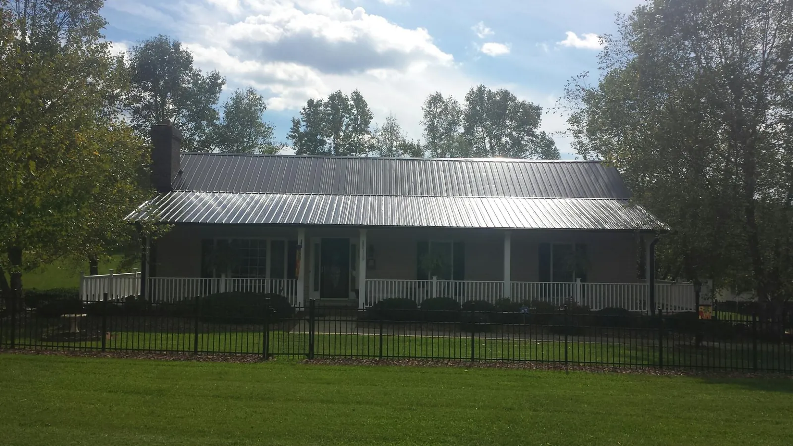 Gray metal roof on a brick ranch with a full width front porch — Gutter Guard Installation work by our crew in Klamath Falls