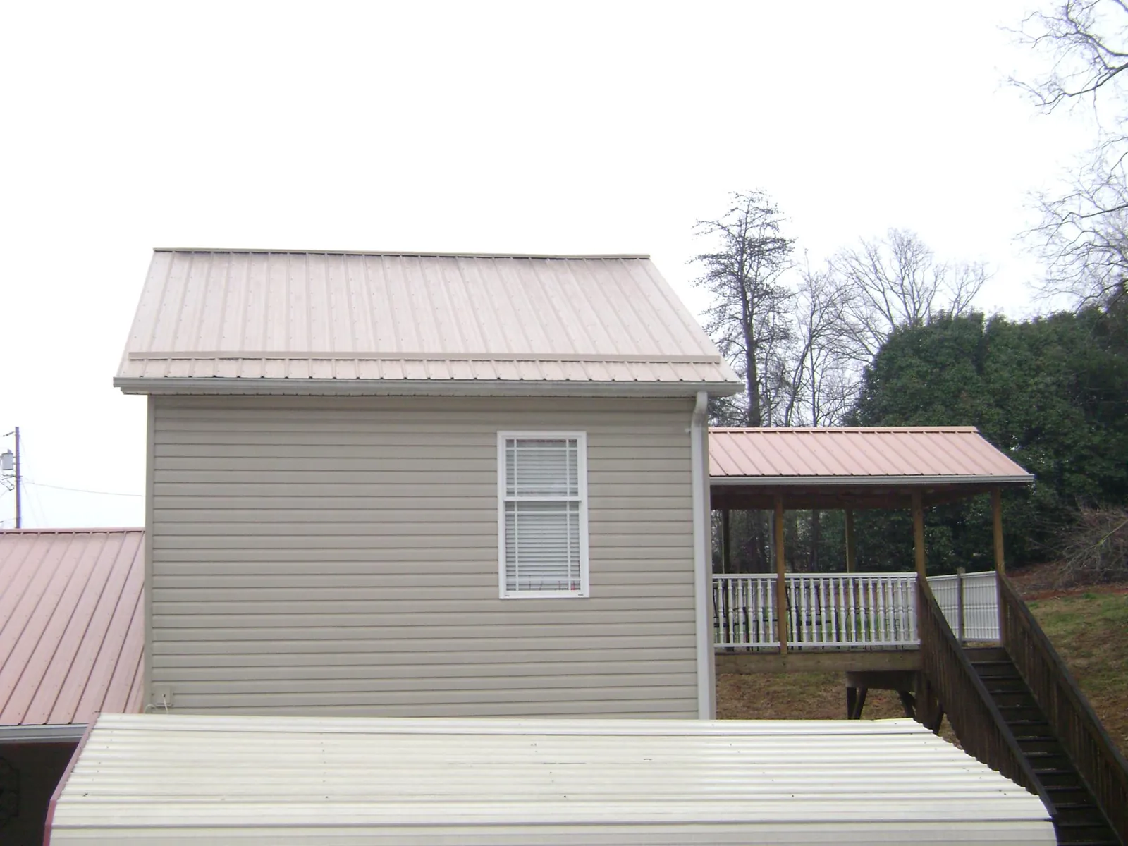 Tan metal roofs on a two story addition and attached porch, from a Roof Replacement job in Klamath Falls