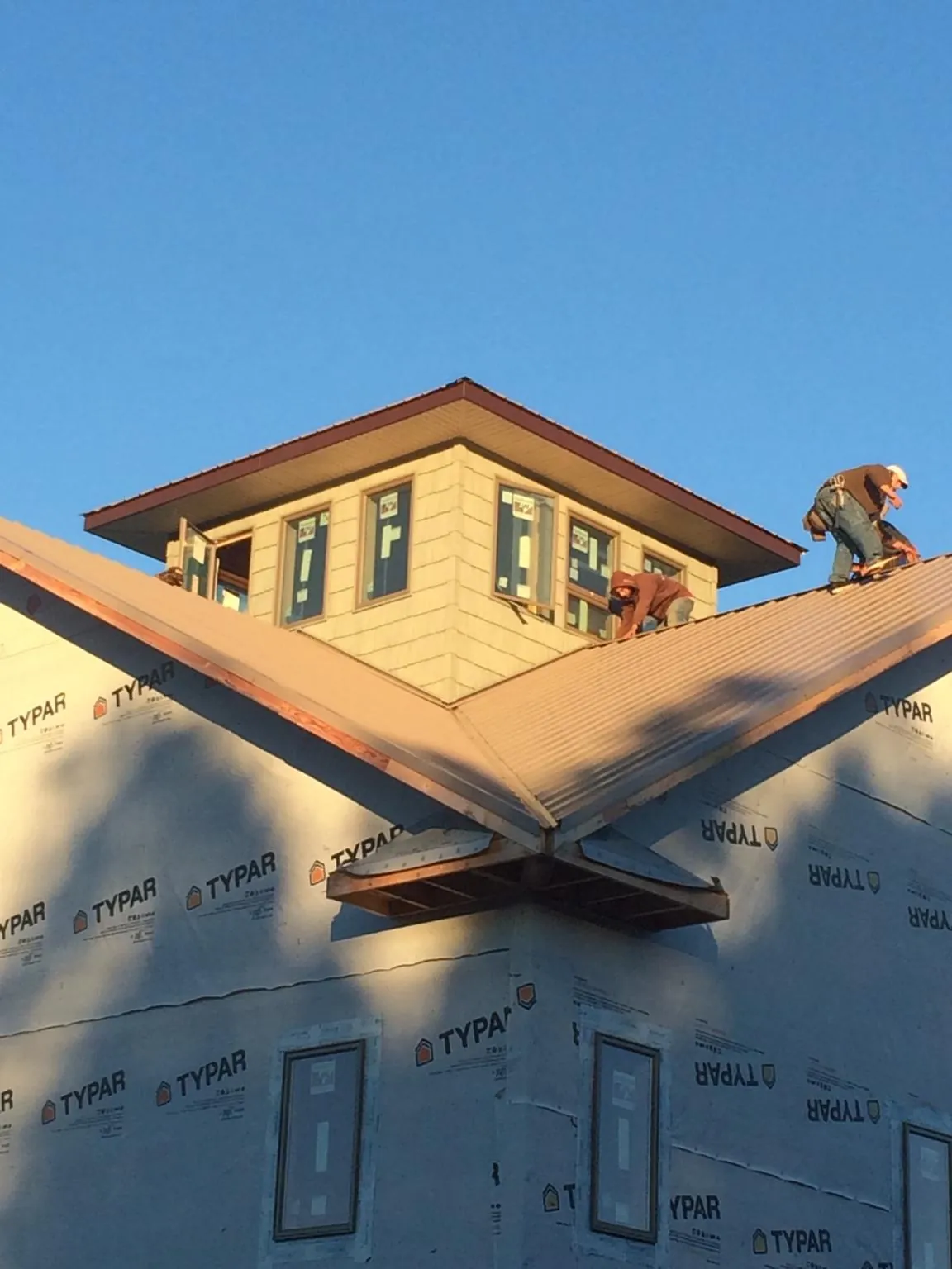Roofers working around a rooftop cupola on a new metal roof at sunset — Roof Waterproofing in Klamath Falls by Roofing Brothers
